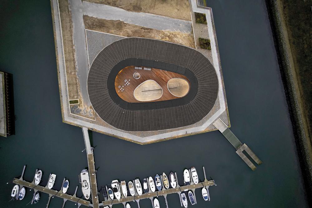 Dem Meer zugewandt steht das runde Gebäude im Yachthafen. Ein Steg ermöglicht den direkten Zugang auf das Wasser.