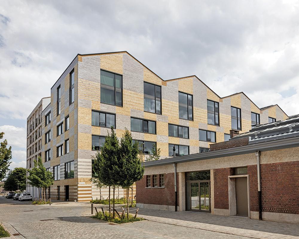 Die industriell anmutende Fassade des Neubaus mit ockergelben, teilweise glasierten Ziegeln nimmt Bezug auf die Gebäude des ehemaligen Hafenviertels.