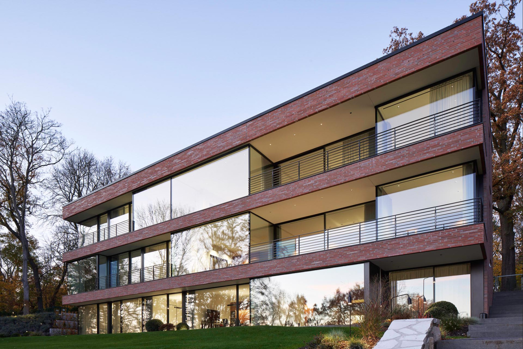 Nur schmale Backsteinbänder im Bereich der auskragenden Deckenplatten unterbrechen die maximal transparente Glasfassade.