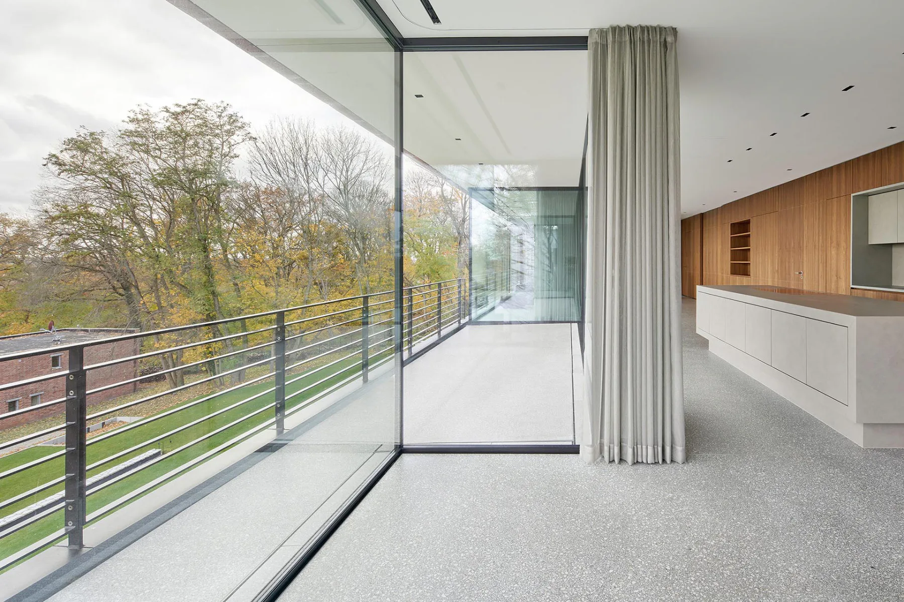 Rücksprünge in der Glasfassade schaffen geschützte Freisitze. In Kombination mit der Glasecke schaffen sie ein architektonisches Highlight.
