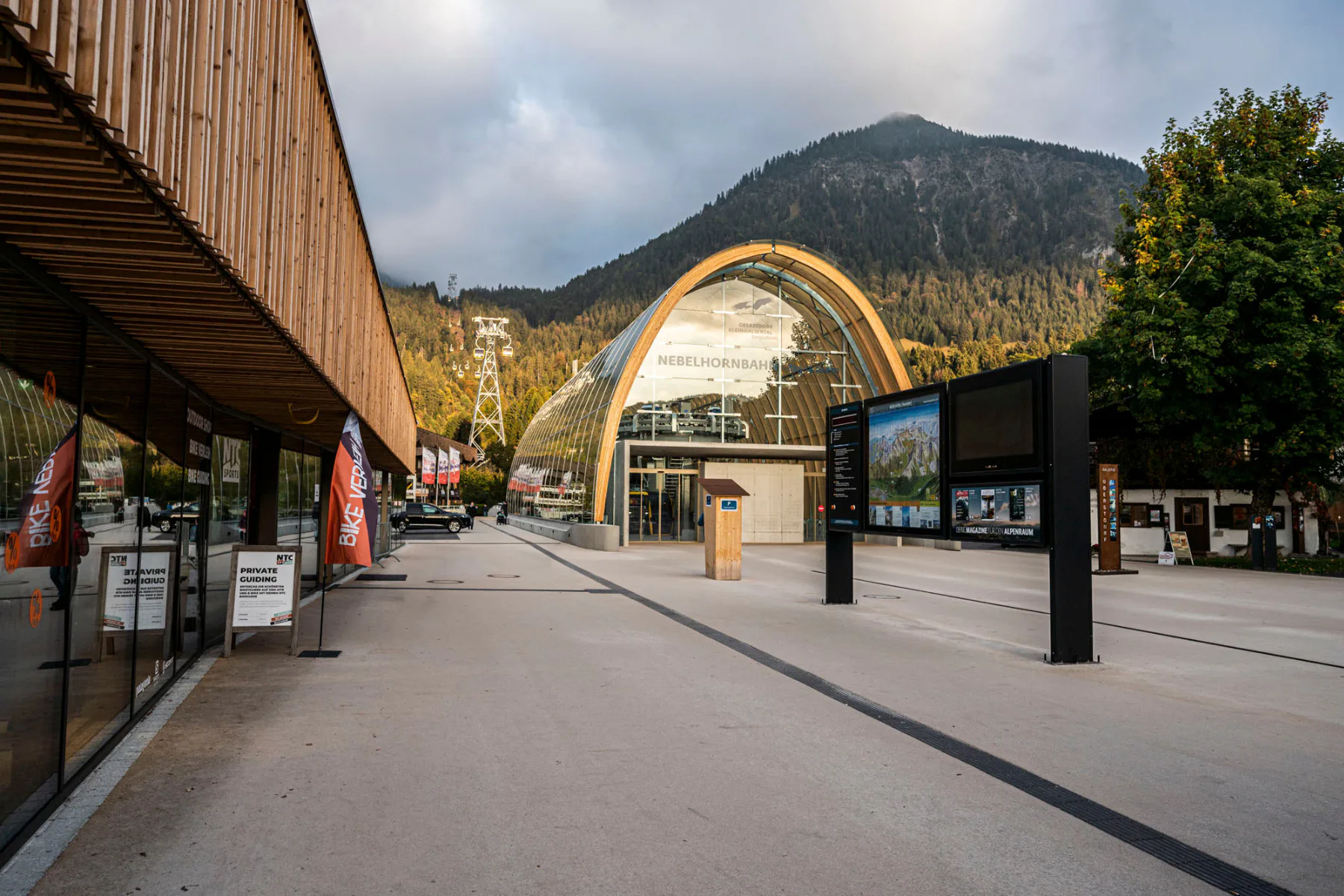 Die transparente Westfassade der Talstation Nebelhornbahn zum neuen Dorfplatz hin, wirkt wie das Eingangsportal in die Bergwelt.