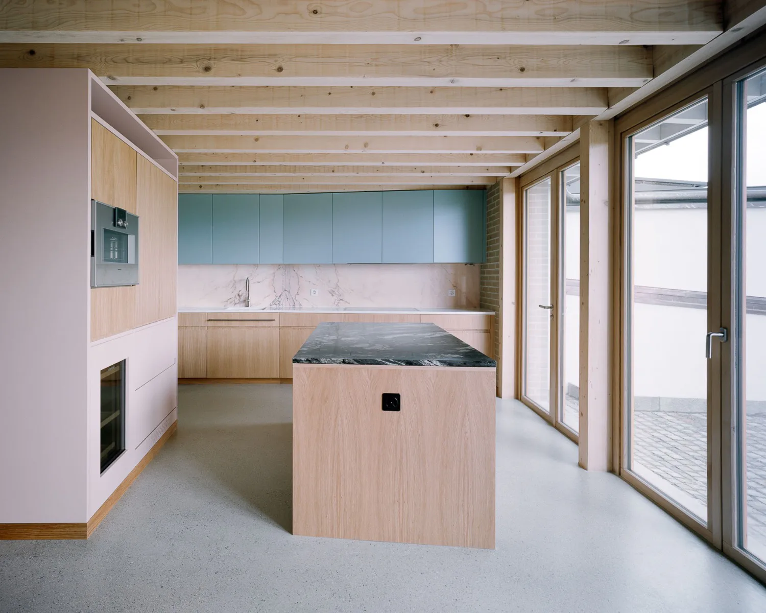 Holz, Naturstein und Pastelltöne charakterisieren die Küchengestaltung.