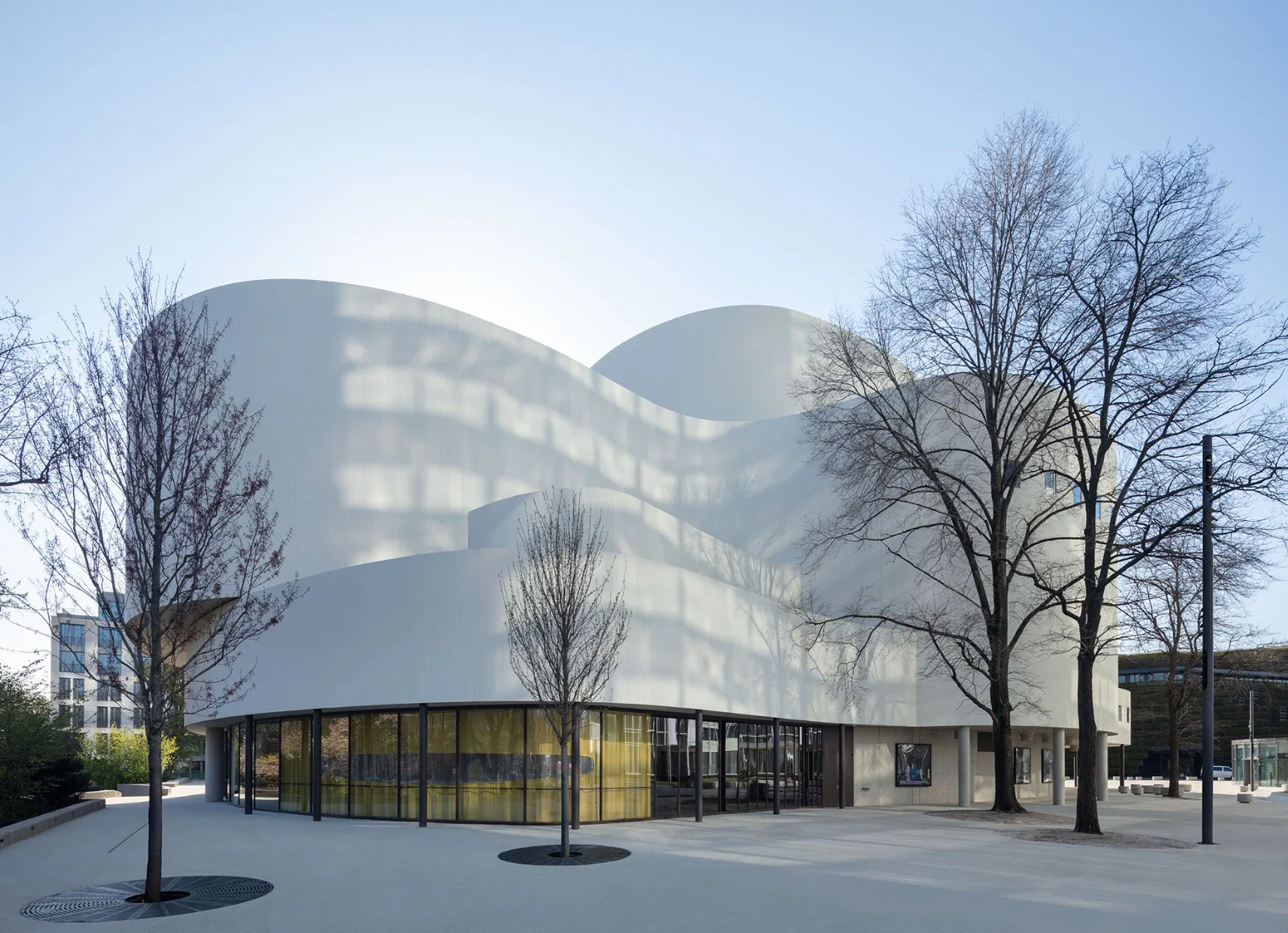 Die geschwungene Fassade dient als Leinwand für die Lichtreflexionen des Dreischeibenhauses.