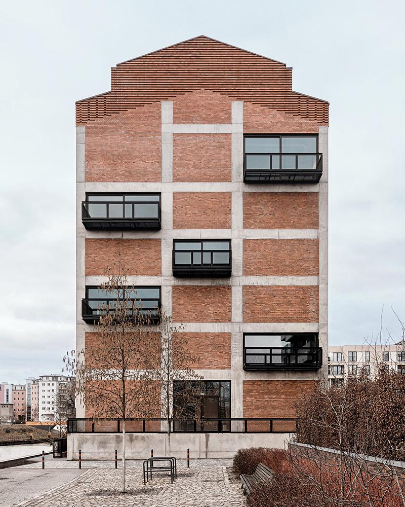 Große Verglasungen und Balkone öffnen das Gebäude zur Stadt. Die entnommenen Klinker wurden gereinigt und an anderer Stelle wieder eingesetzt.
