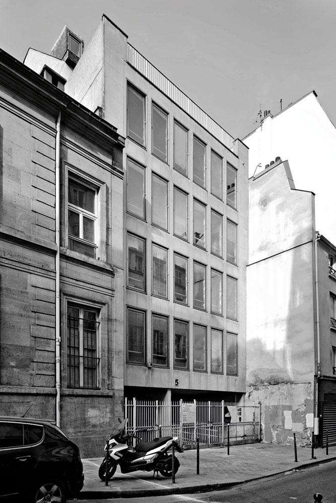 Die Fenster zur Straße wurden durch eine Ganzglasfassade ersetzt. Der Vorhang aus perforiertem PVCTextil bietet Blend- und Sichtschutz.