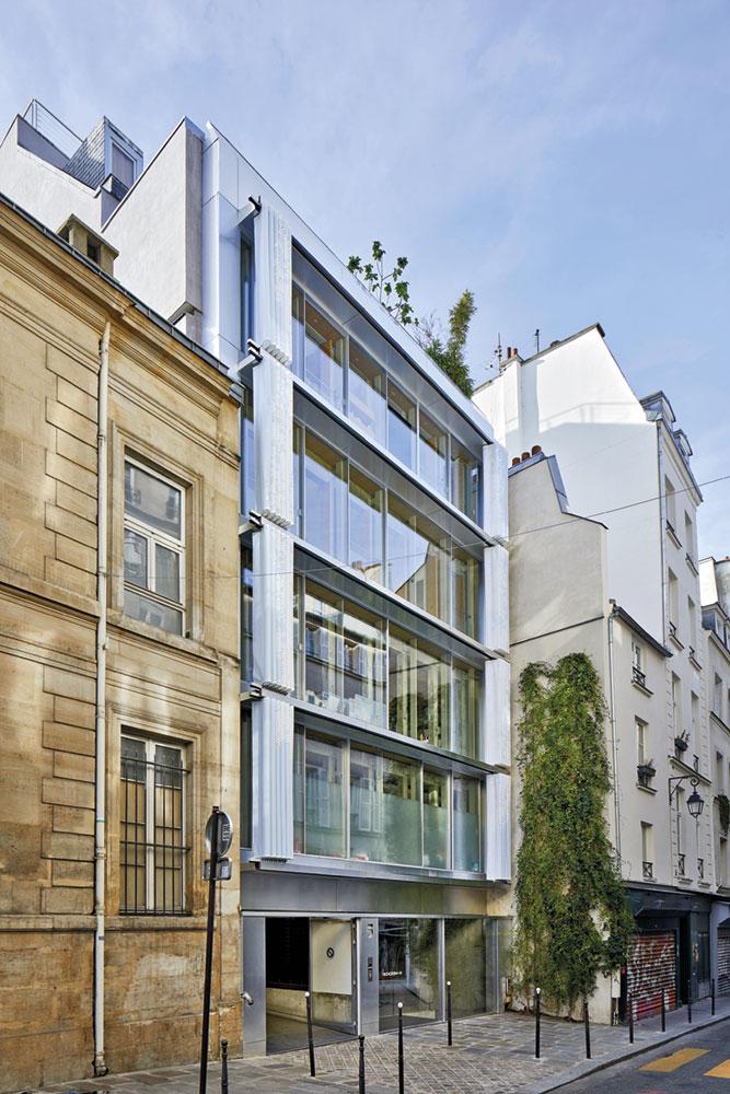 Die Fenster zur Straße wurden durch eine Ganzglasfassade ersetzt. Der Vorhang aus perforiertem PVCTextil bietet Blend- und Sichtschutz.