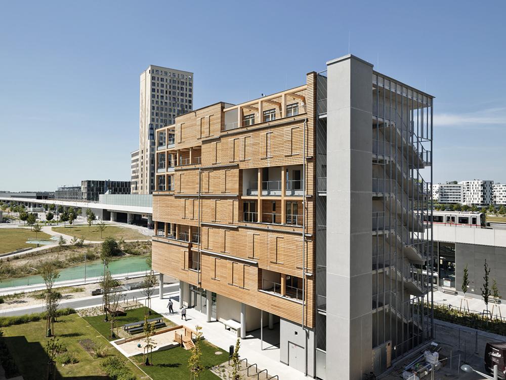 Die modulare Holzkonstruktion der Wohn- und Büroeinheiten sitzt auf dem Sockel des öffentlichen Bereichs im Erdgeschoss, der in Beton ausgeführt ist.