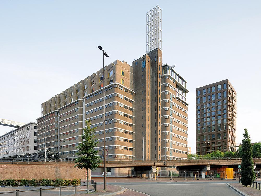 The historic warehouse of the Philips corporation built in the 1940s is an icon of modern architecture. Caruso St John Architects mastered the challenge of renovating the industrial heritage building without impairing its character. On the roof, a new three storey residential structure was created, in addition to a market hall on the ground floor, a parking garage above it and spaces for experimentation for young firms where products were stored in the past.