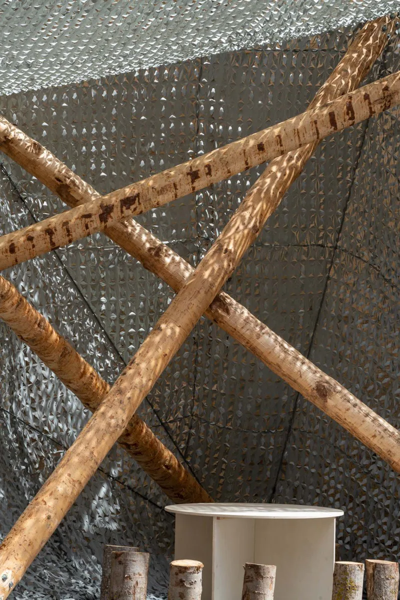 Gefertigt ist die Holz-Installation aus bis vier bis zu sieben Meter langen Stämmen entrindeter Kiefern, die über Stahlseile und -lager verbunden sind.