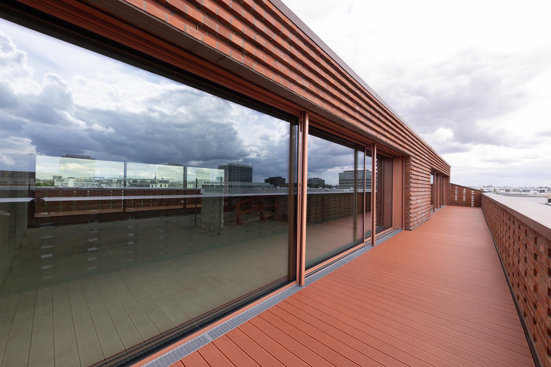 Die Räumlichkeiten der Aufstockung öffnen sich fast vollständig mit großformatigen cero Schiebefenstern von Solarlux. Ton in Ton mit der Klinkerfassade und dem Bodenbelag nehmen sich die Rahmen- und Fensterprofile optisch vollständig zurück.