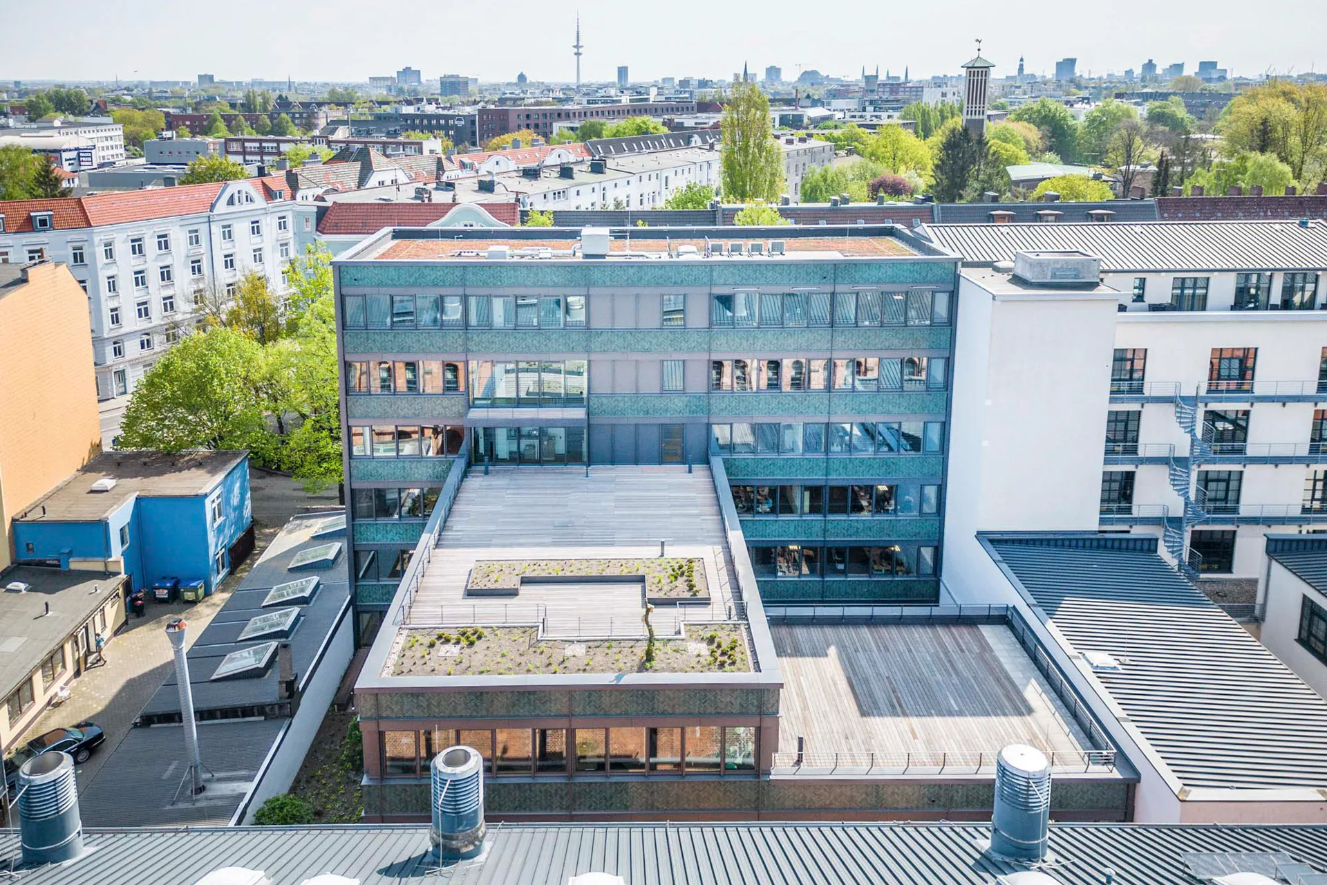 Die grüne Keramikfassade greift den kleinteiligen Charakter der umgebenden Backsteinfassaden auf.