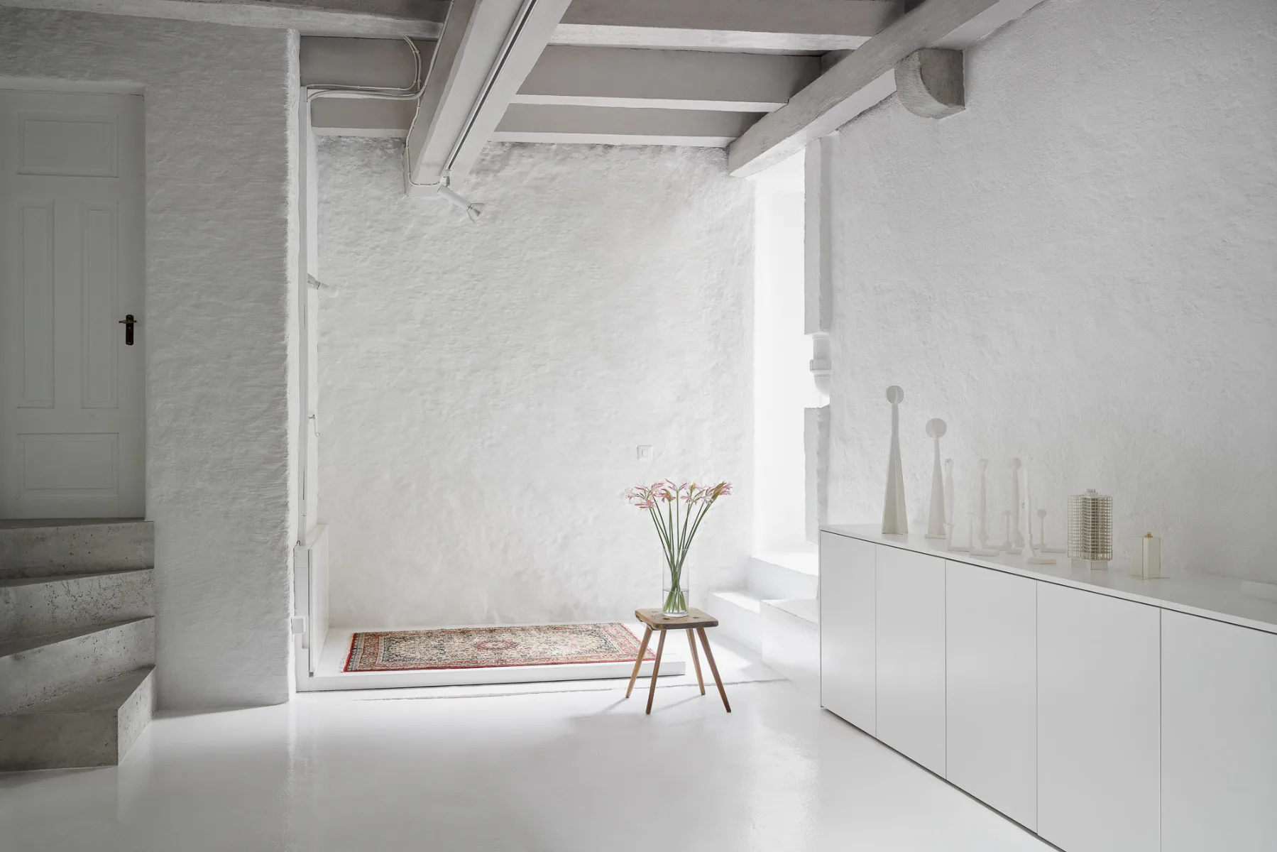 Untergeschoss mit Treppe, die zum Badezimmer führt und weissen Stufen, die zum Innenhof führen.