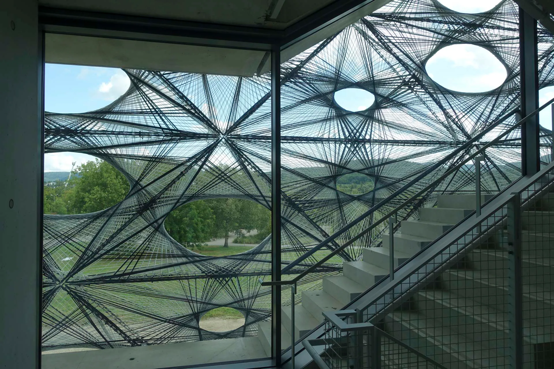 Wie ein gewobenes Kleid umgeben die im Werk vorgefertigten Elemente aus Kohlenstoff und Glas den transparenten Kubus.