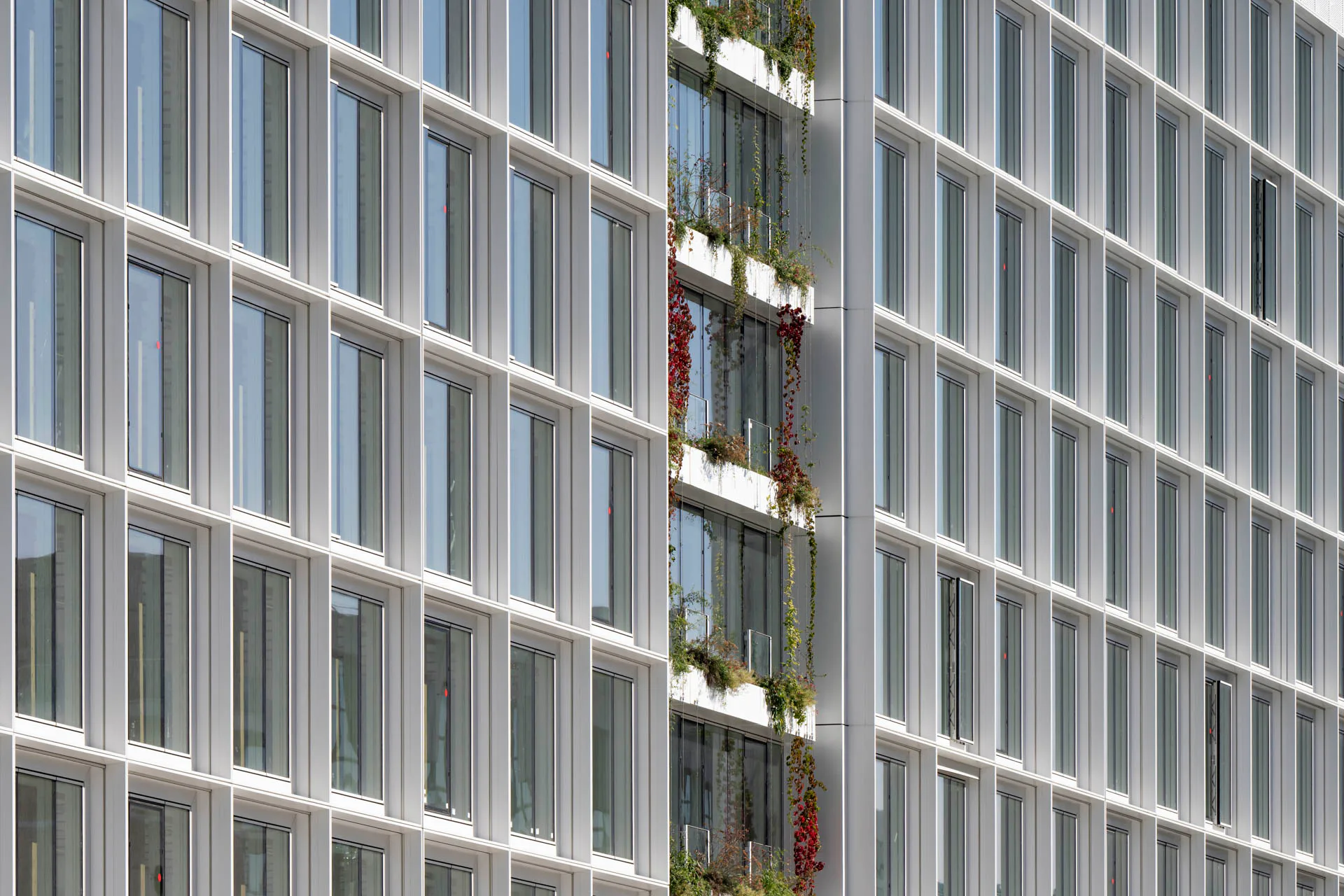 Die regelmäßige Rasterfassade bildet das Tragskelett des Gebäudes aus Holz und Beton nach außen ab.