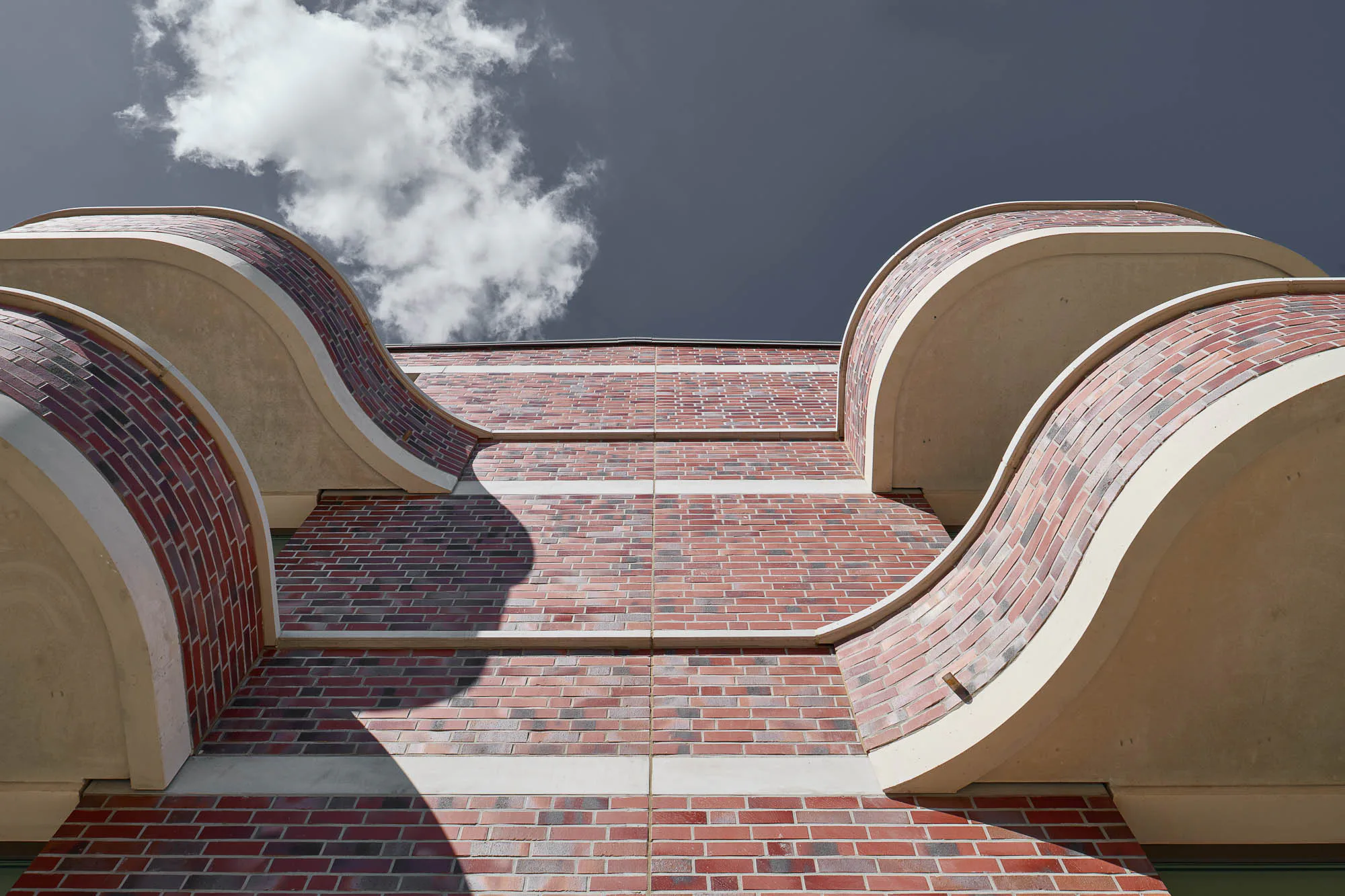 Die leicht asymmetrisch geschwungenem Balkonelemente sind geschossweise gespiegelt angeordnet.