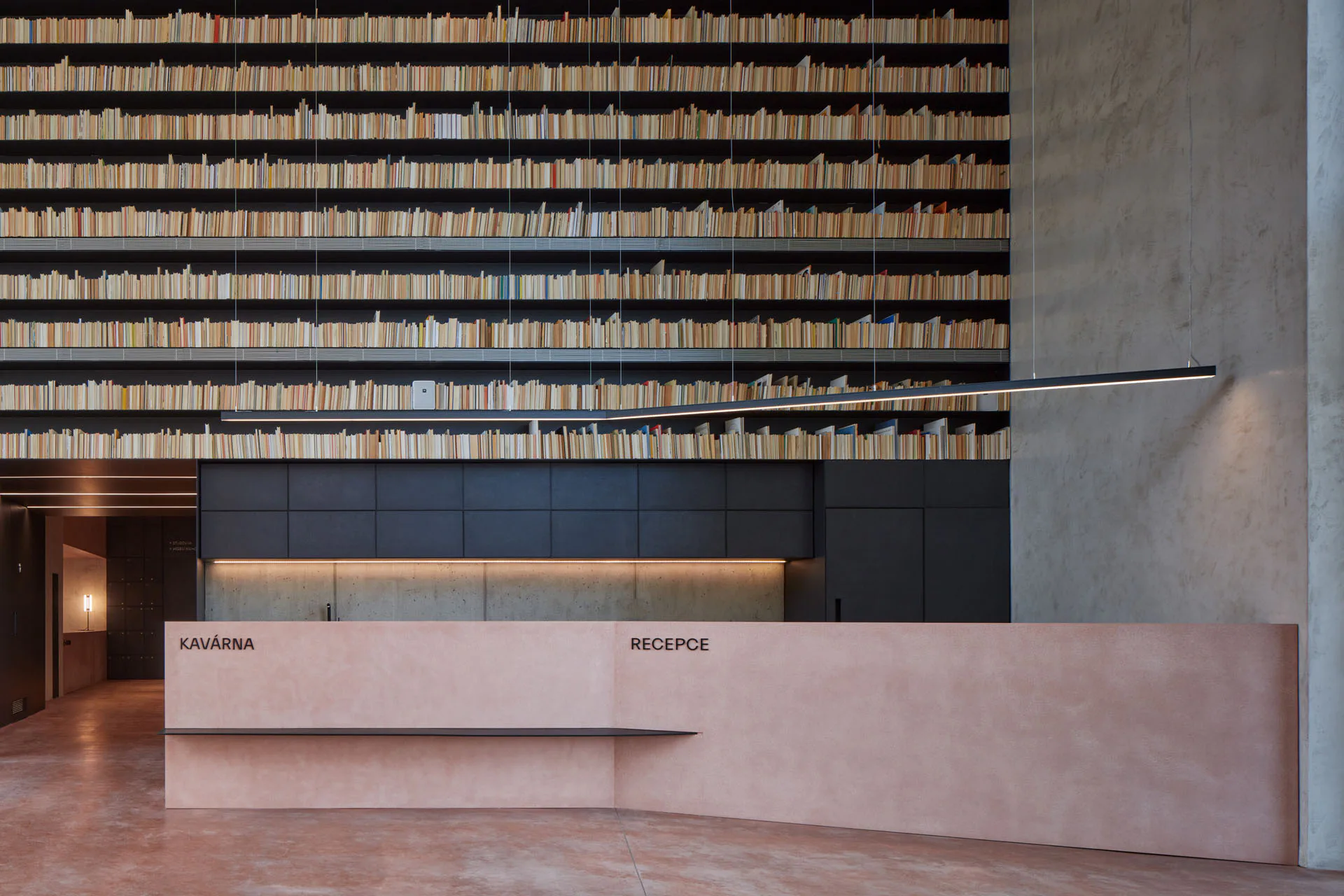 Der Empfangsbereich liegt vor einer raumhohen Bücherwand.