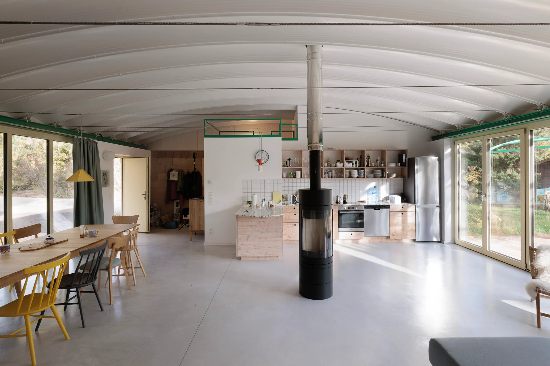 Tonnenförmig gewölbte Sandwichelemente aus dem Industriebau überspannen den großen Raum stützenfrei.