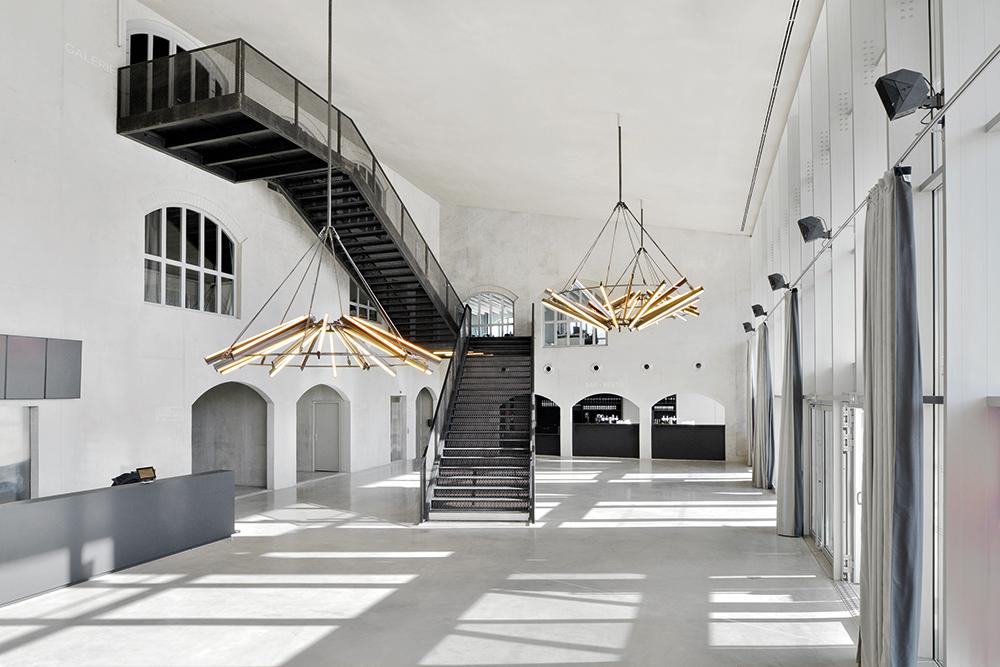 Minimalistische Kronleuchter aus schwarzem Stahl erhellen das Foyer hinter der verglasten Eingangsfassade.