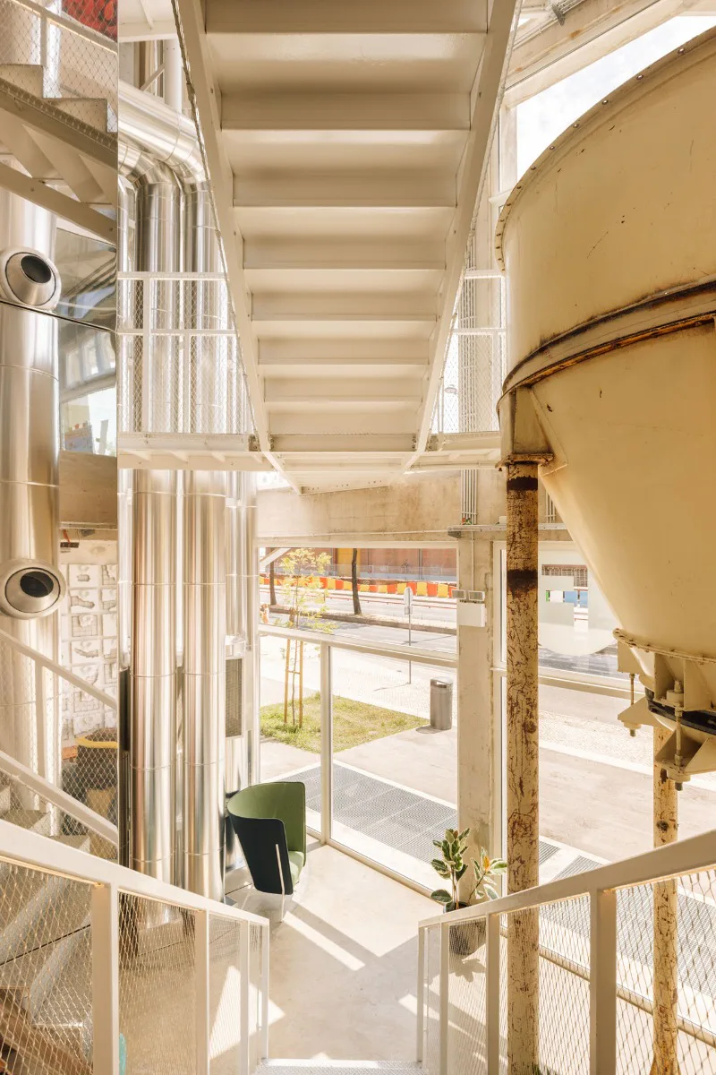 Weiße Treppen aus Stahl ergänzen die erhalten gebliebenen Maschinen der ehemaligen Fabrik.