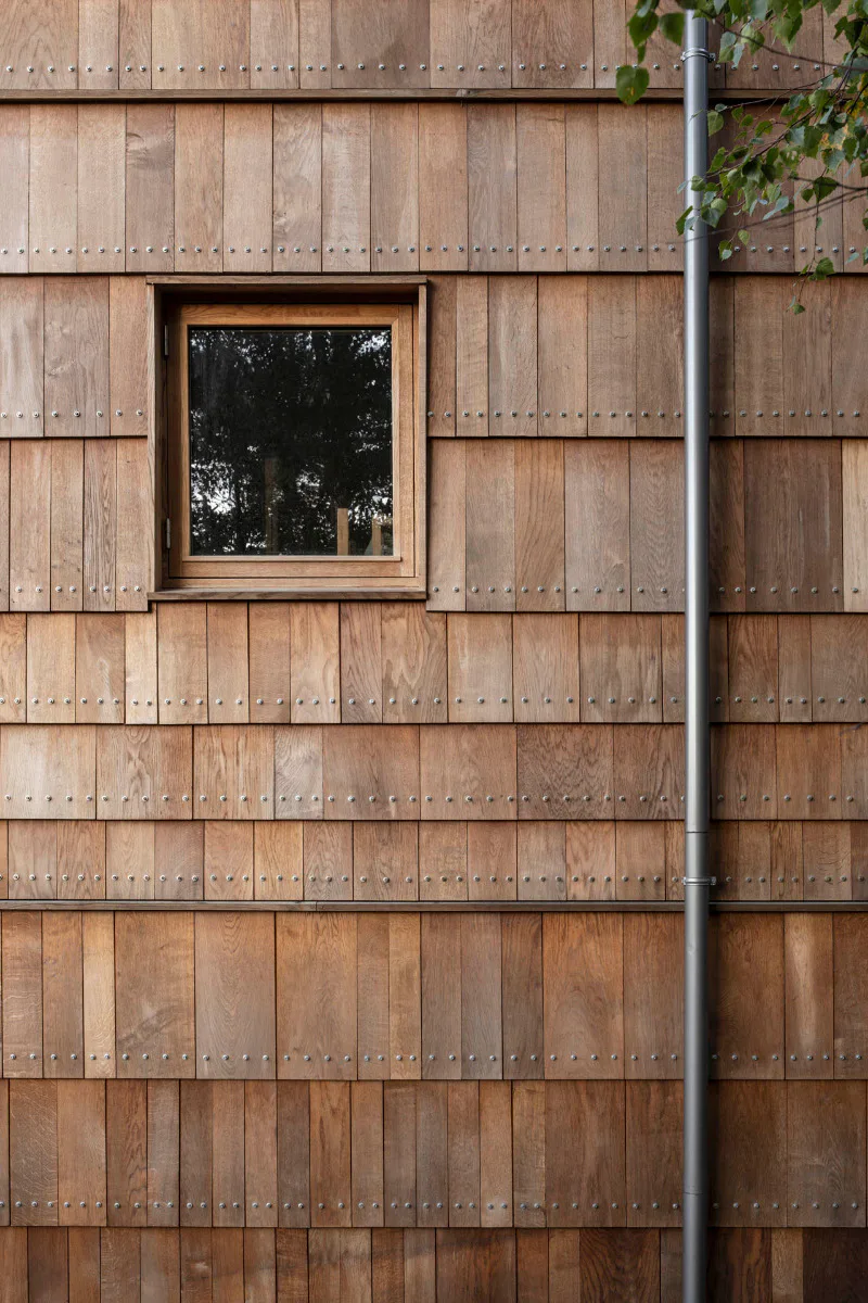 Für die Schindelfassaden und -dächer nutzten die Architekten Restholz aus der Fußbodenproduktion.