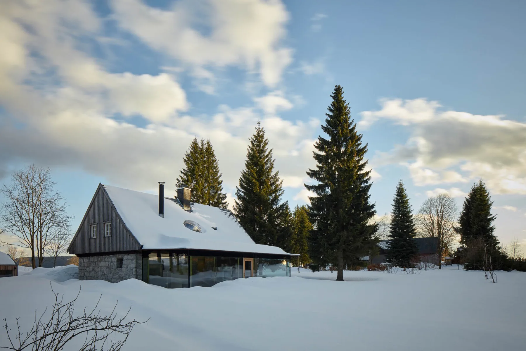 Mjölk Architekti haben das 130 Jahre alte Wochenendhaus im Isergebirge mit viel Glas zeitgemäß adaptiert.