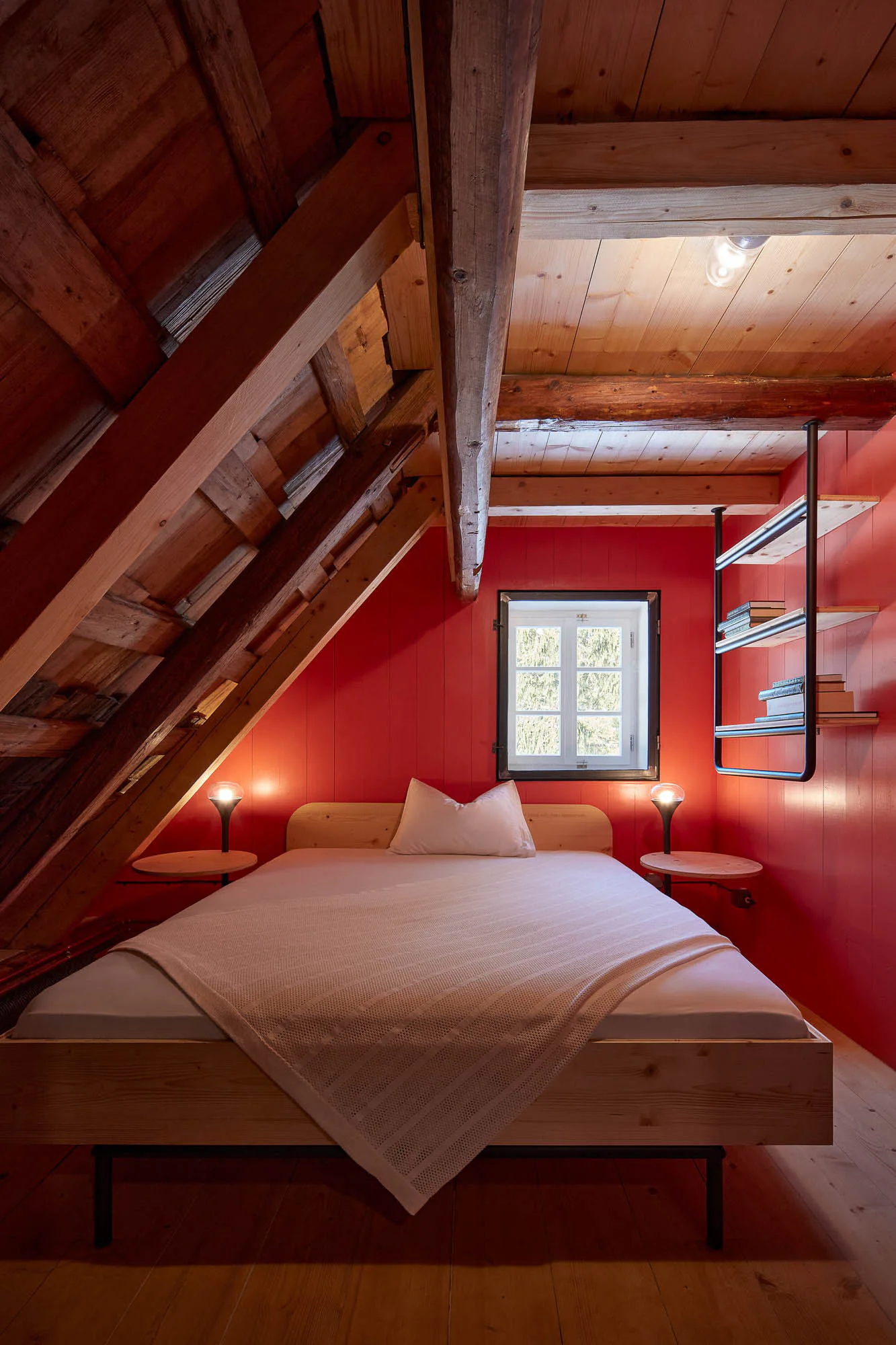 Im Schlafzimmer sind die holzgetäfelten Wände in einem satten Rot gestrichen.