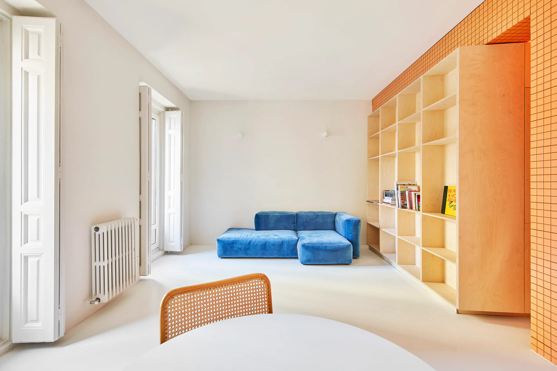 Ein mit Birkensperrholz verkleideter Kern im Zentrum der Wohnung enthält ein Bücherregal, das zur Sofaecke im Wohnzimmer ausgerichtet ist.