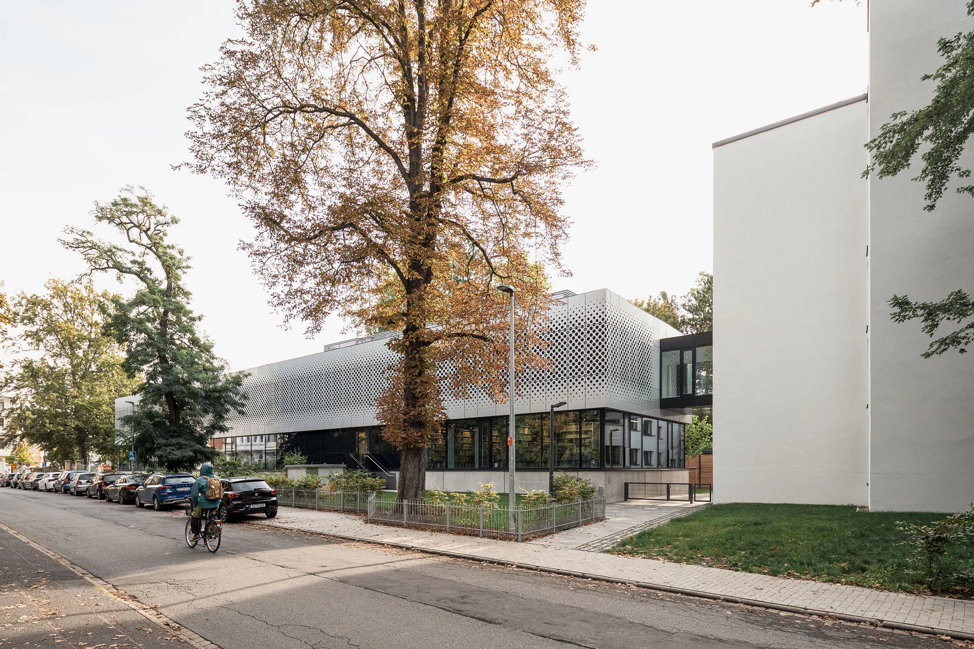 Zwei sanierte Bestandsgebäude – im Nordosten eine klassizistische Villa und im Südwesten ein ehemaliges Schwesternwohnheim – flankieren den Bibliotheksneubau.
