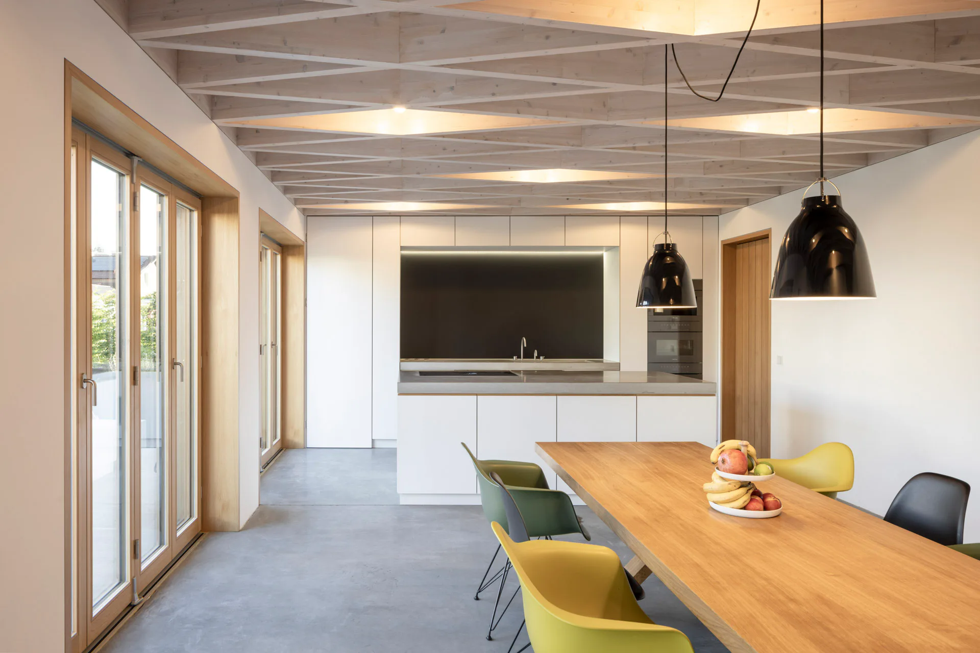 Rautenförmig angeordnete Holzbalken tragen die Decke über dem Koch- und Essbereich.