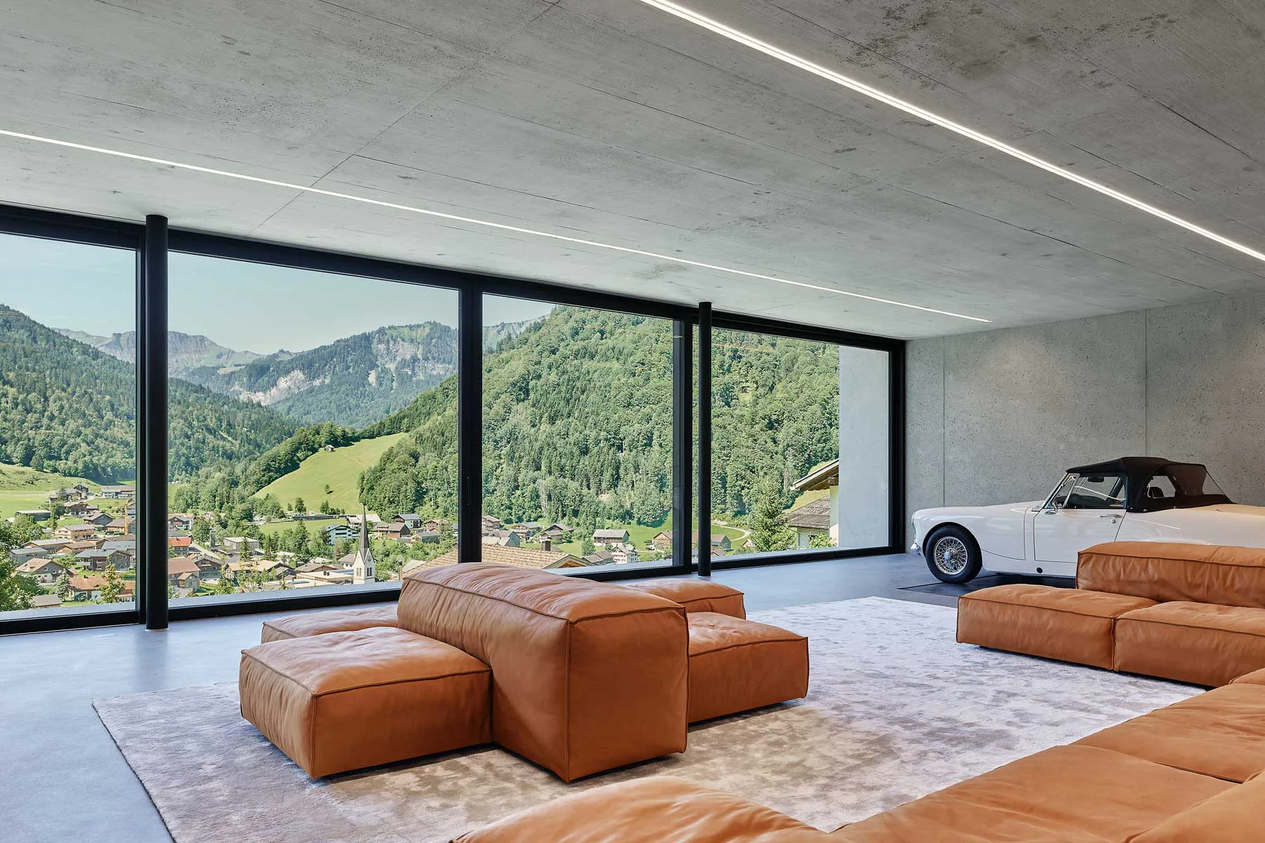 Der Wohnraum öffnet sich über eine imposante Panoramaverglasung zur Landschaft.