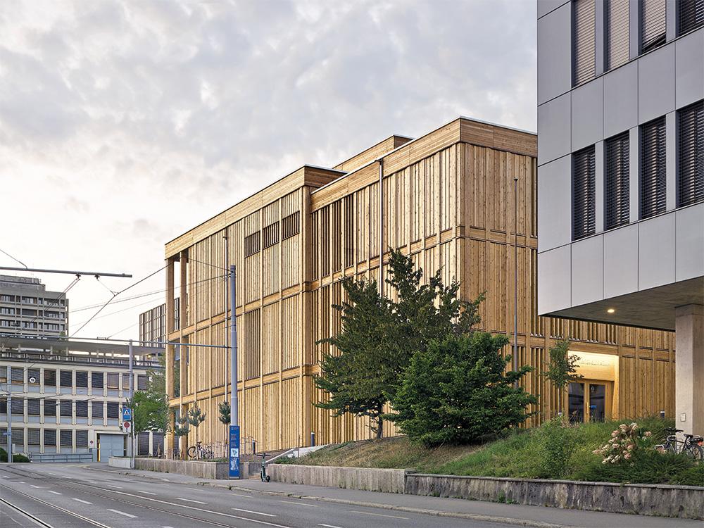 The tripartite, larch clad timber building stands at an exposed position on a tight curve on Zurichberg. Trams travel past three sides of the building.