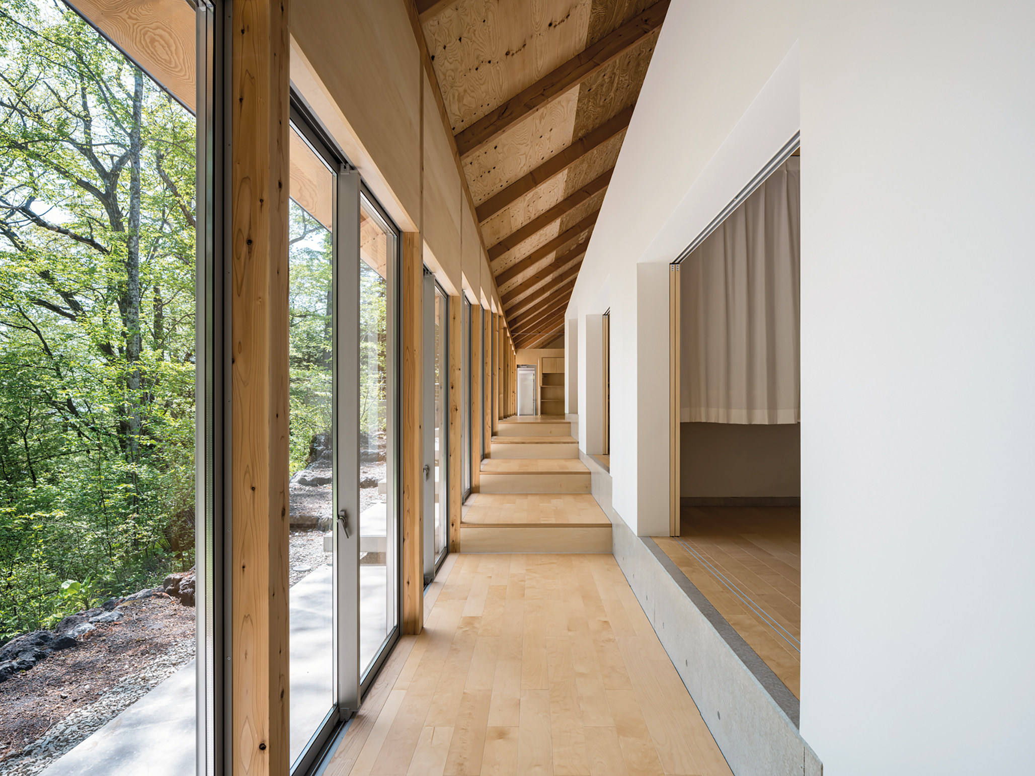Sliding doors in the glass facade and to the bunklike bedrooms link the house spatially with the
forest along its entire 30m length.