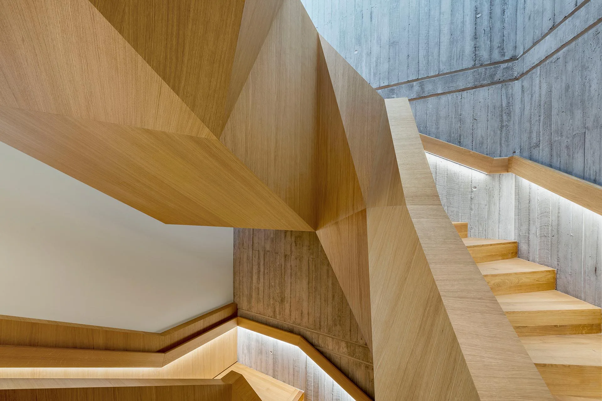 Die maßgefertigte Holztreppe im Verwaltungsneubau wirkt skulptural.