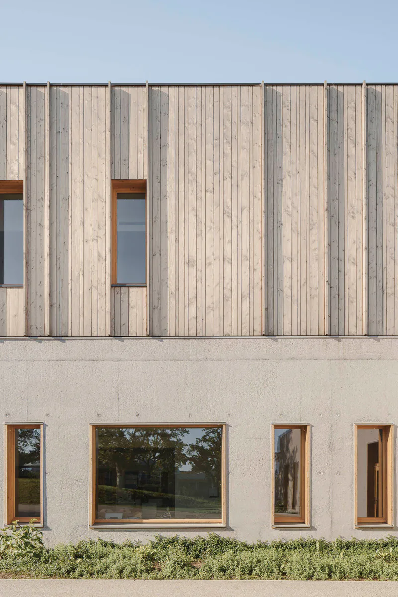 Der Sockel der Vorschule ist in sandgestrahltem Sichtbeton ausgeführt. Das riegelförmige Obergeschoss ist eine Holzrahmenkonstruktion mit senkrechter Douglasien-Schalung.