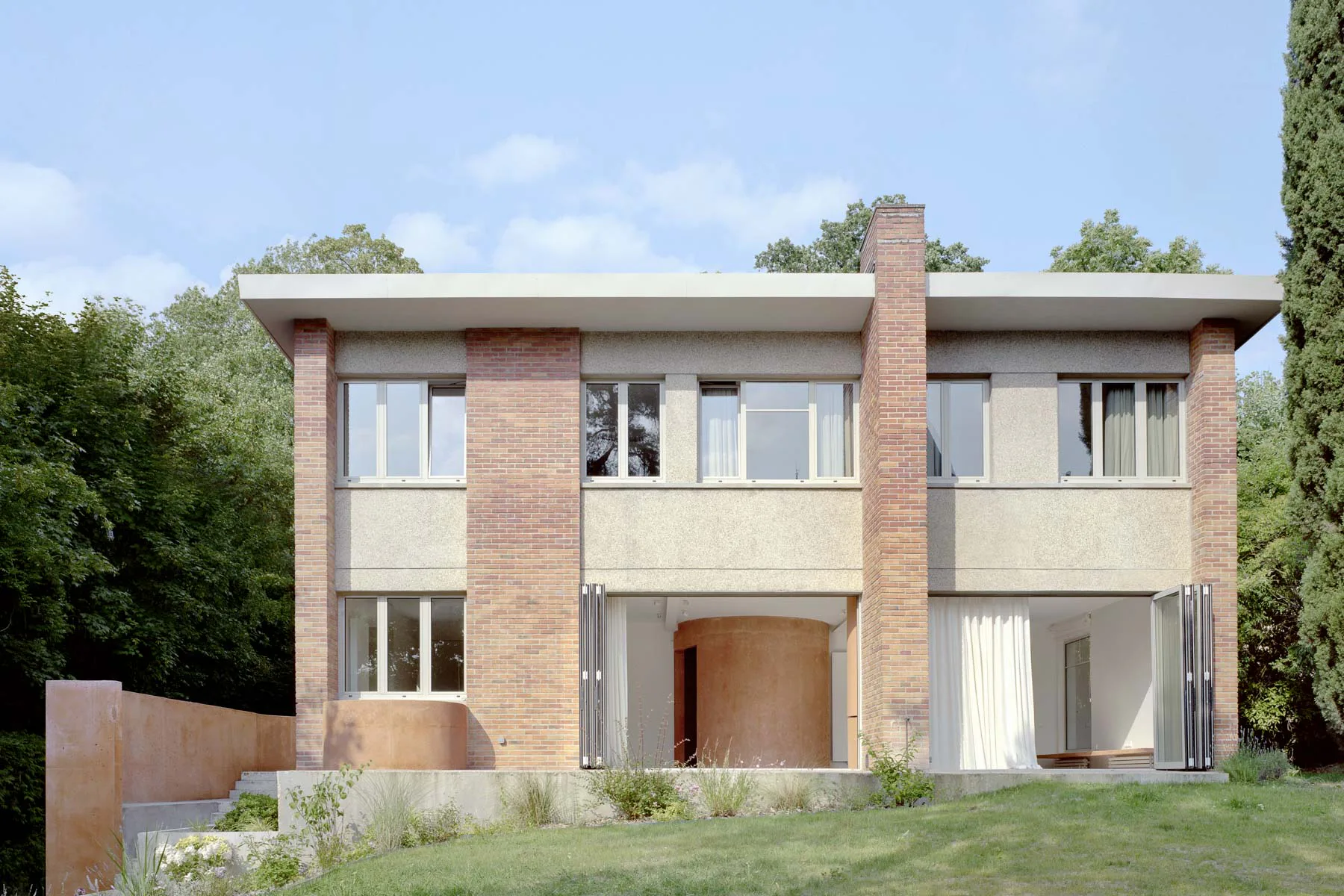 Die architektonischen Eingriffe aus ziegelrotem Recyclingbeton werten das Wohnhaus aus den 1950er-Jahren bedeutend auf.