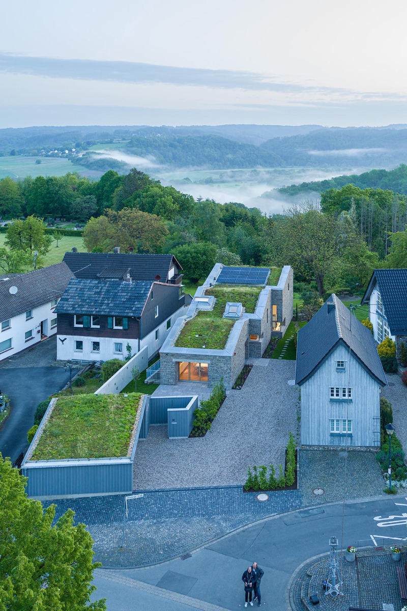 Das Atelierhaus wurde in ein bestehendes Ensemble aus Fachwerk und Bruchstein behutsam eingefügt. Durch die intensive Dachbegrünung des Neubaus „schwappt“ die Natur in das Dorf hinein.