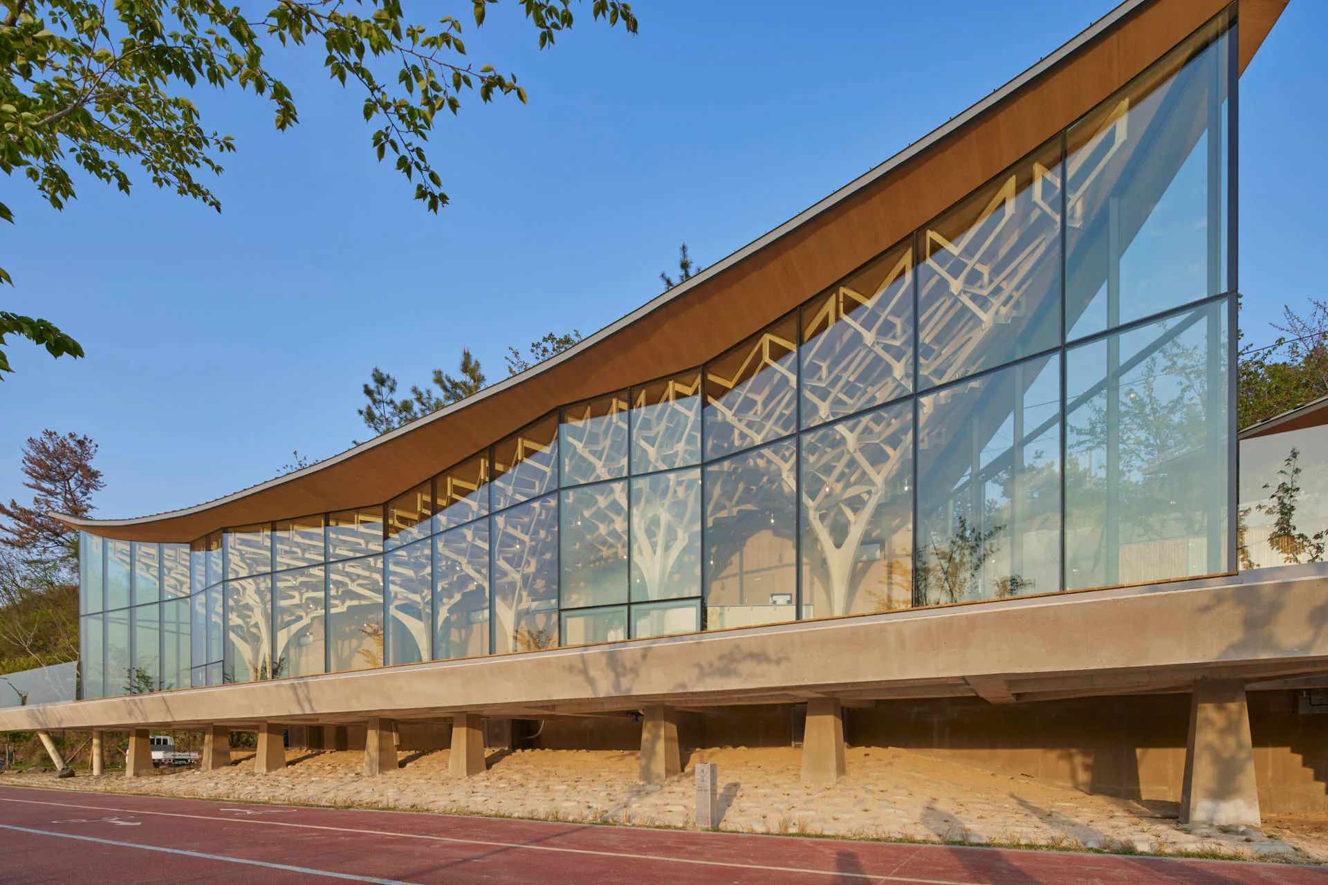 Ein mächtiger Betontisch trägt den Pavillon, der mit seiner Glasfassade und den Holzstützen ausgesprochen leichtgewichtig daherkommt.