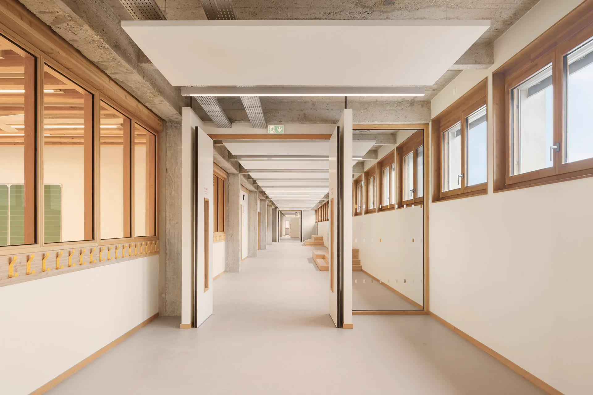 Im Inneren ergänzen Holz und großflächige Verglasungen die Betonstruktur und sorgen für ein freundliches Ambiente.