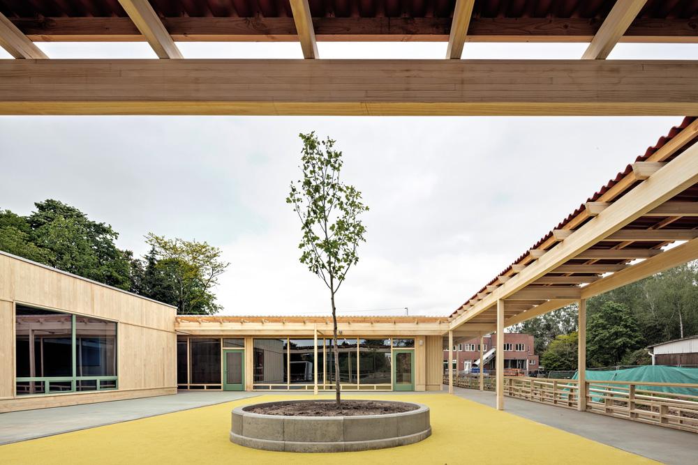 An zwei Seiten ist das Erweiterungsgebäude von einer Holzpergola eingefasst. Die Kinder gelangen auf kurzen Wegen ins Freie.