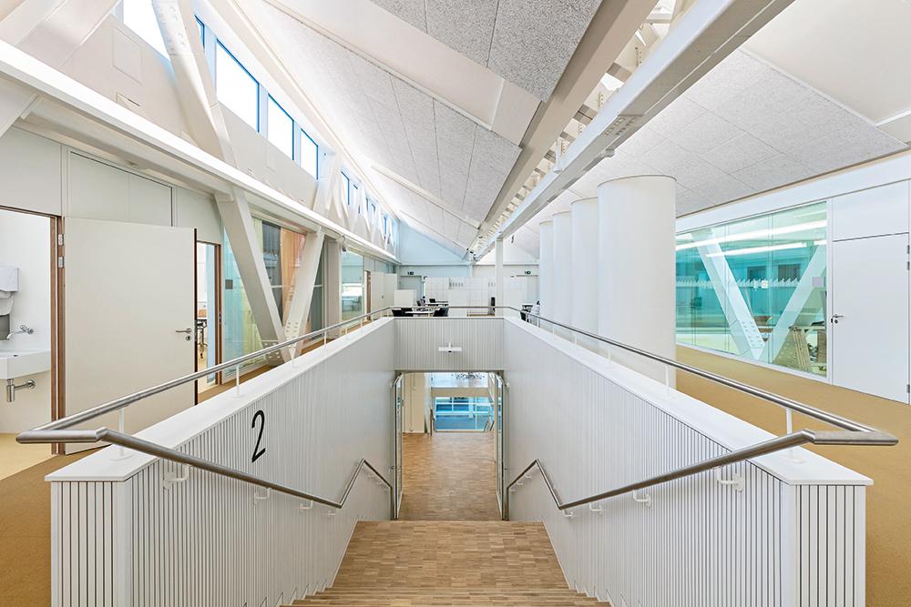 Großzügige Treppen führen zu den Unterrichtsräumen im Dachgeschoss. Nach Norden ausgerichtete Sheddächer sorgen für gleichmäßige Lichtverhältnisse.