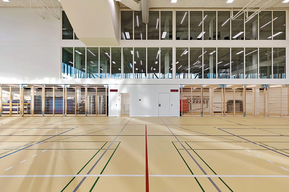 Raumhohe Glaswände trennen Sporthalle und Aula. Dadurch entstehen spannende Blickbezüge zwischen den einzelnen Geschossen.