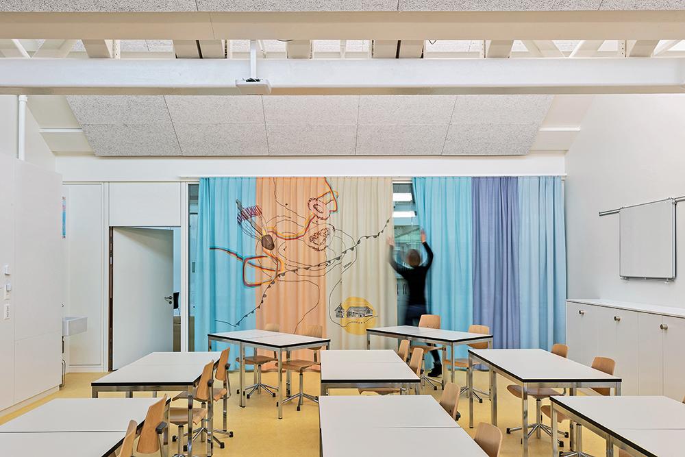 Der Unterricht spielt sich hinter Glaswänden ab. Textile Vorhangsysteme setzen farbliche Akzente und steuern den Grad an Intimität.