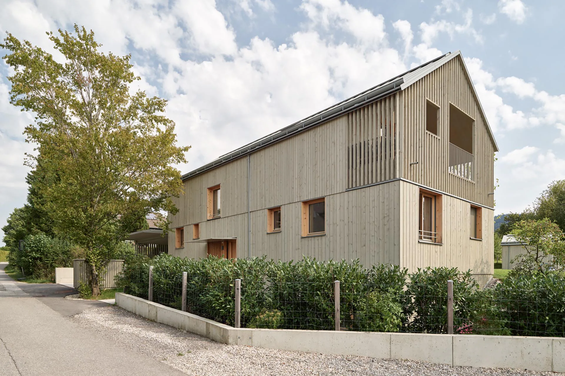 Der Eingangsbau an der Straße beherbergt auf drei Ebenen die Individualräume. An der Fassade wechseln sich offene Loggien mit geschlossenen Bereichen ab.