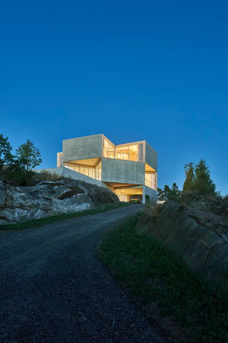 Das Ferienhaus besitzt viele verglaste Einschnitte in der Fassade, die verbleibenden Außenflächen sind mit Sichtbeton geschlossen.