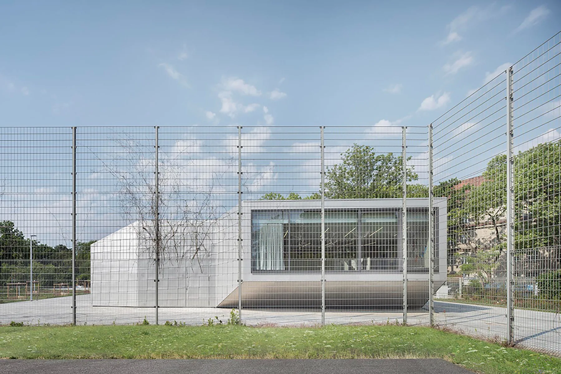 Auf der einen Seite das Schulhaus, auf der anderen Sportflächen und dazwischen der neue, eingeschossige Pavillon.