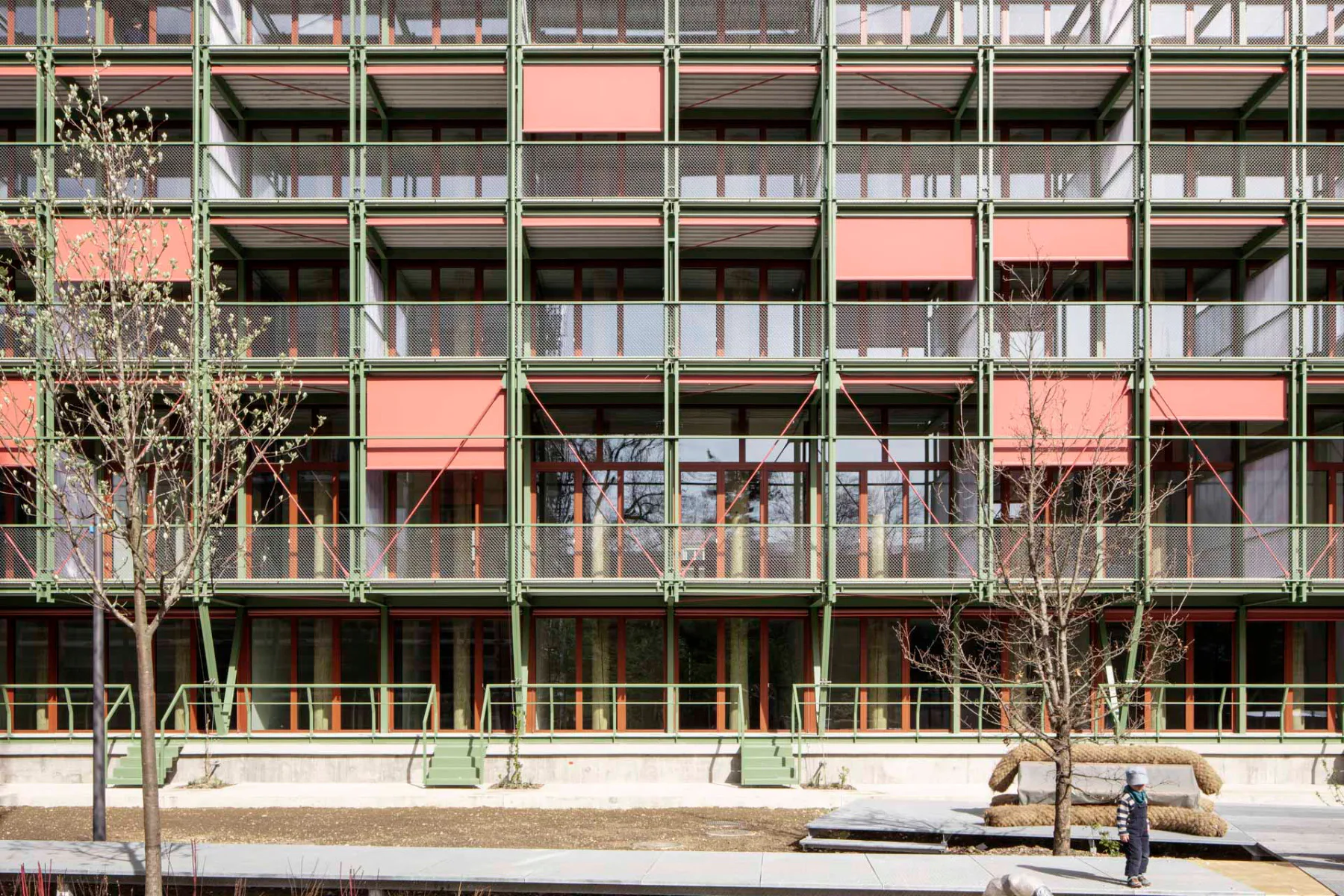 Mit seiner auffälligen farbigen Fassade hebt sich das Wohnhaus im Stadtraum ab. Grüne und rote Metallelemente fügen sich zu einem lebhaften Gesamtbild zusammen.