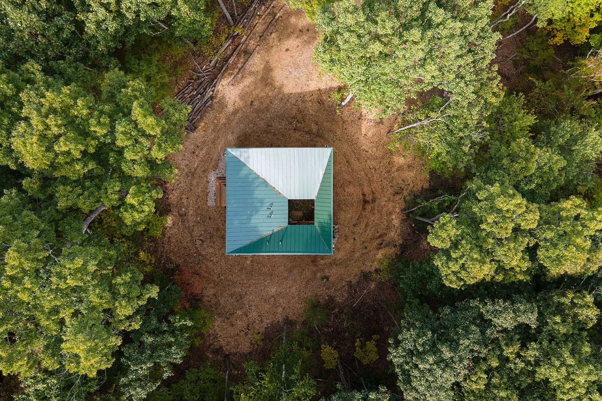 Das Haus steht mitten im Wald, erreichbar nur zu Fuß oder mit dem SUV. Eine quadratische Öffnung entwässert die Dachflächen nach innen auf den Waldboden.