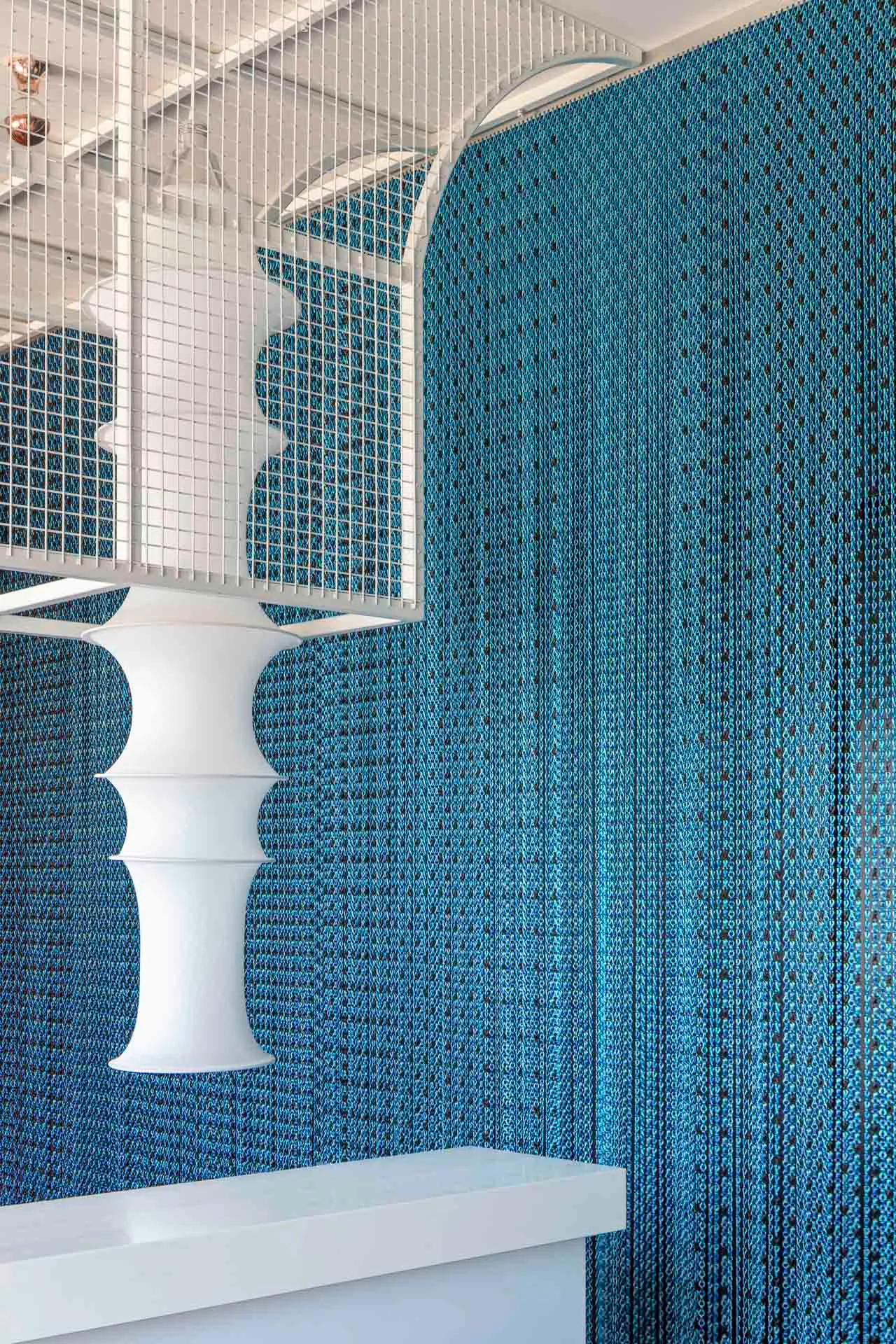 Im weiß beschichteten Metallgitter über der Theke hängt eine Falkland-Lampe, entworfen von Bruno Munari.