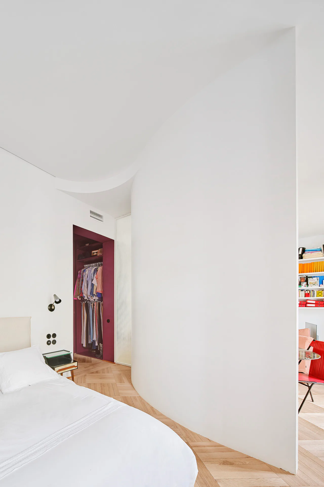 Das Schlafzimmer wird vom Essbereich durch eine geschwungene Wand abgetrennt.
