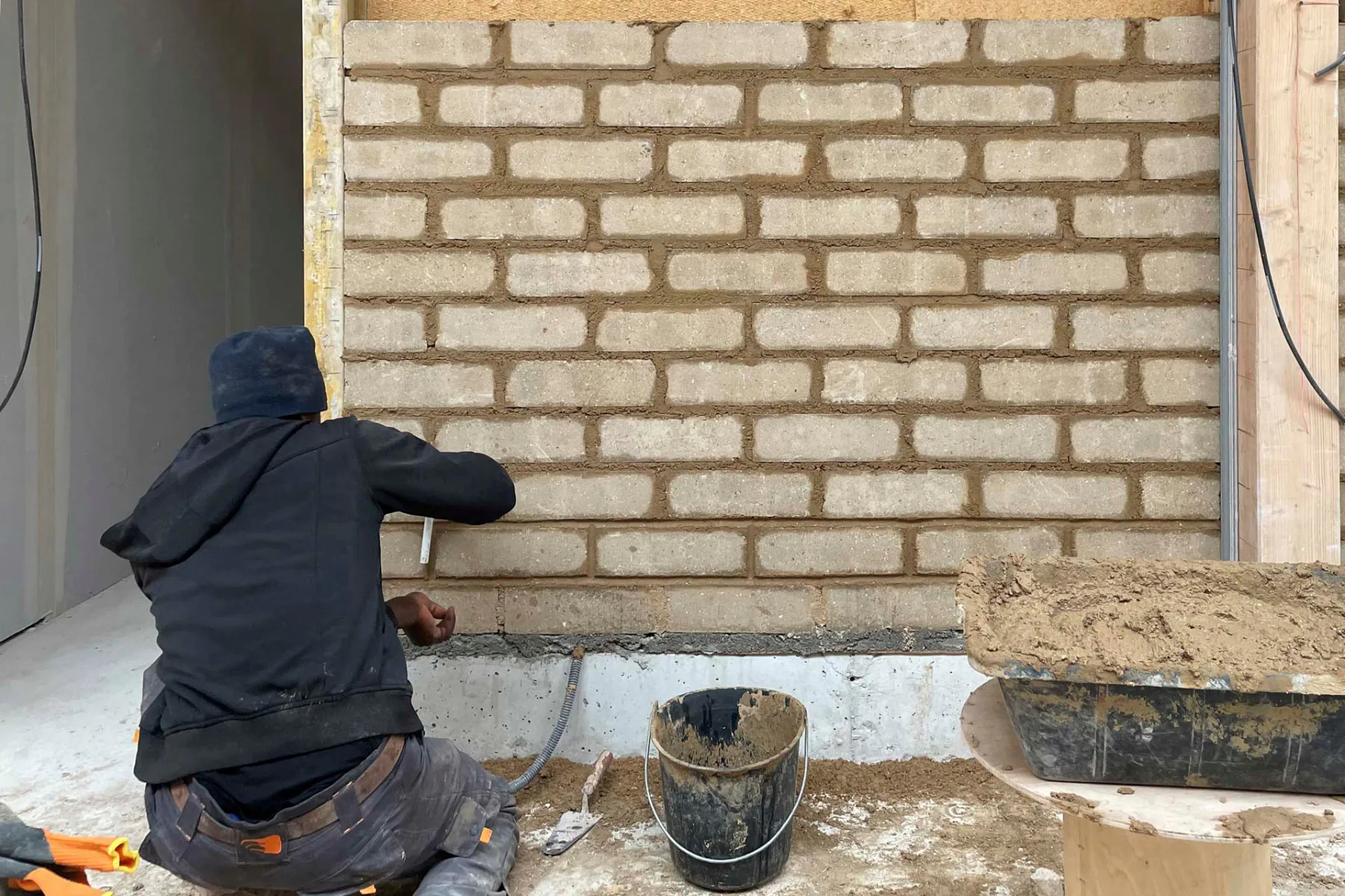 Entstehung der Konstruktion aus Holz, Lehmputz, gepressten Erdziegeln sowie eine Isolierung aus Holzfasern und Kork.